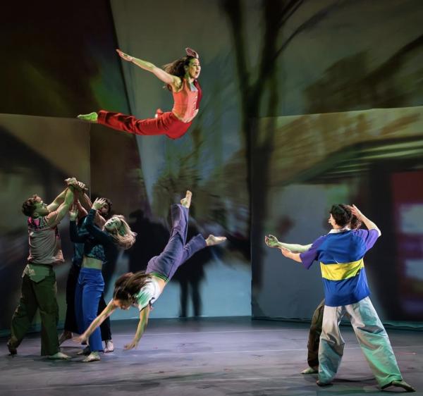 Photo of a performer flying through the air as another leaps across the stage