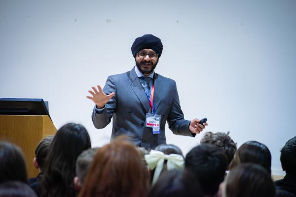 Photo of DCI Signh stood in front of a group of students, smiling as he delivers his talk