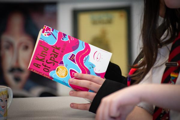 Photo of a student holding the A Kind of Spark book. The child's face is out of the photo.